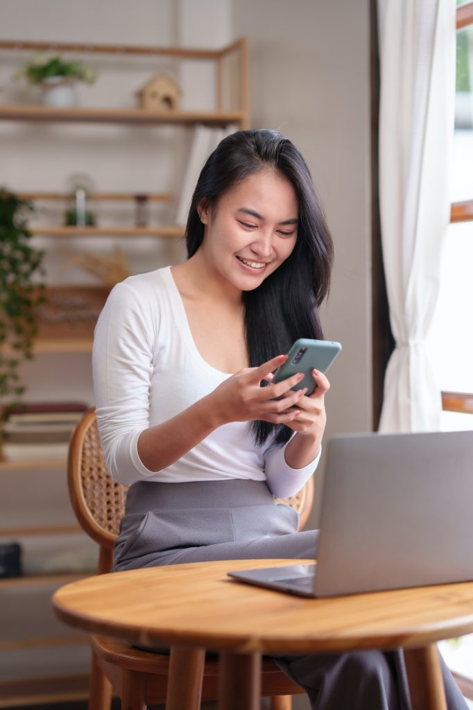 Beautiful Asian woman sitting at home working on her laptop and playing various applications on her