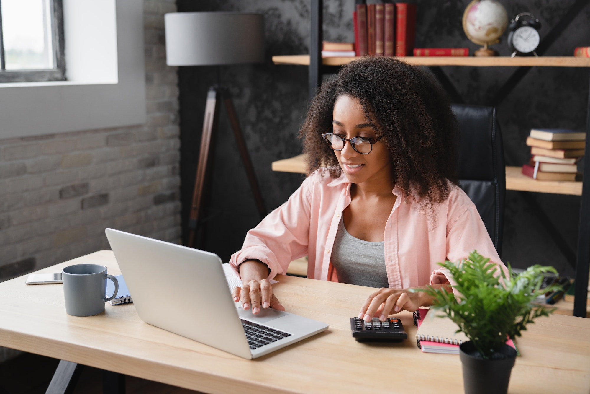 Freelancer counting funds domestic bills on calculator using laptop for e-banking,debt and loan