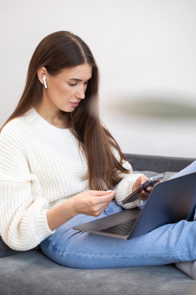 Online payment, a woman holds a smartphone and uses a credit card for online purchases.