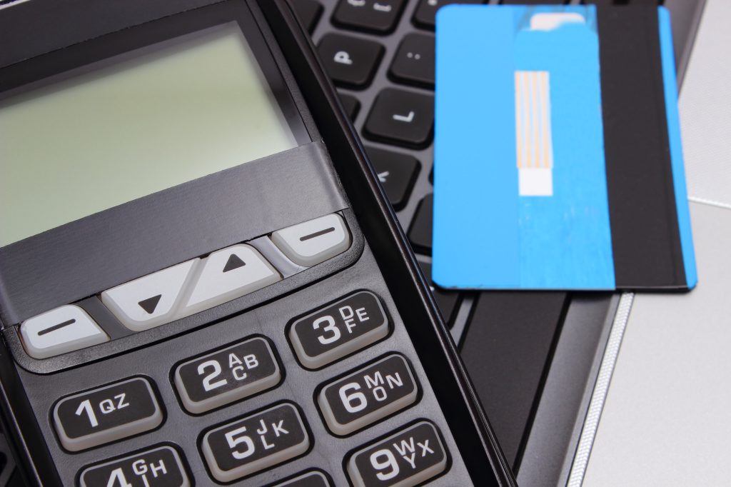 Payment terminal and credit card on laptop keyboard