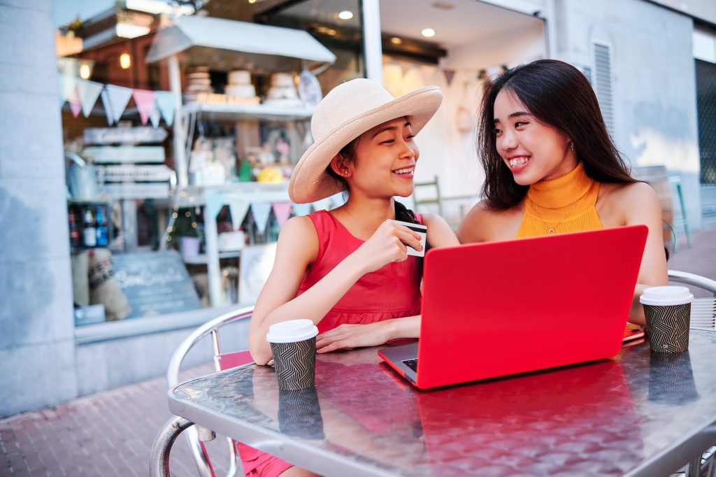 two asian girls using a credit card to pay or purchase using a notebook