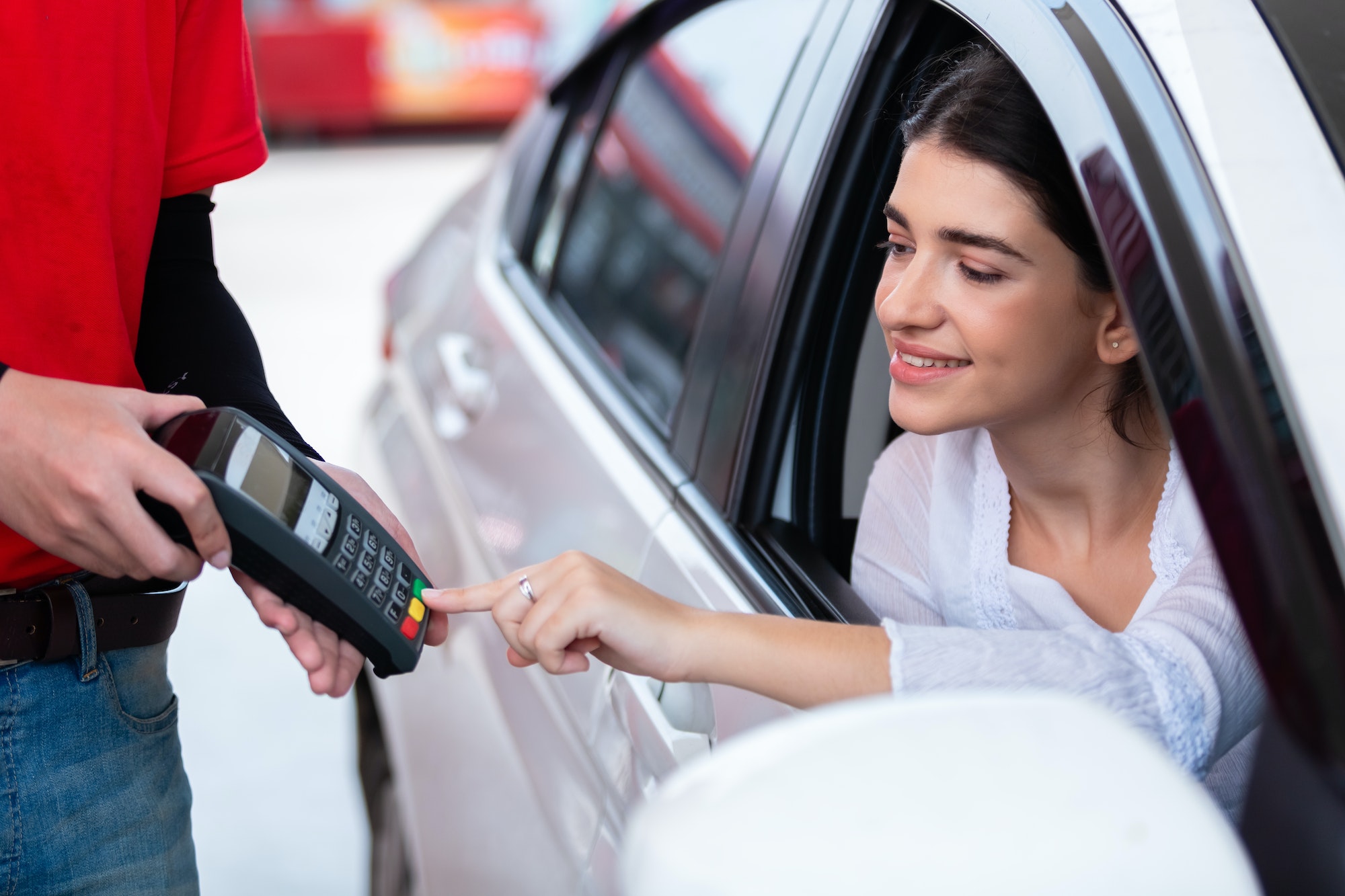 Woman in car paying card reader payment terminal after refuel car.